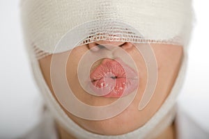 Woman with bandaged face blowing a kiss