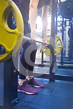 Woman with a barbell doing exercises in the gym