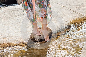 Woman with bare feet standing next to the running river