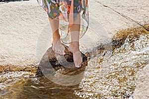 Woman with bare feet standing next to the running river