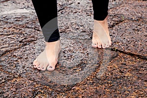 Woman bare feet walking on wet rocky pavement