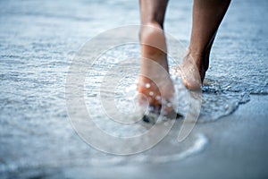 Toe Woman bare foot walking on the summer beach. close up leg of young woman walking along wave of sea water and sand on the beach photo