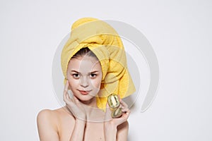 woman with bare shoulders with a yellow towel on her head kiwi in her hands clean skin