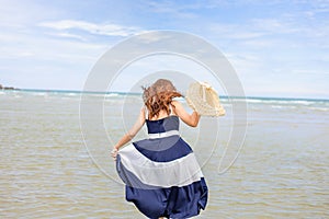 Woman barefoot hold hat and walking on summer along wave of sea water and sand on the beach