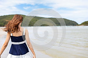 Woman barefoot hold hat and walking on summer along wave of sea water and sand on the beach