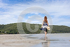 Woman barefoot hold hat and walking on summer along wave of sea water and sand on the beach