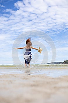 Woman barefoot jump in the water on summer along wave of sea water and sand on the beach