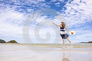 Woman barefoot jump in the water on summer along wave of sea water and sand on the beach