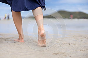 Woman barefoot walking on the beach at  summer along wave of sea water and sand