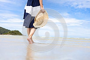 Woman barefoot walking on summer along wave of sea water and sand on the beach