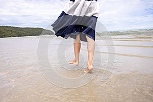 Woman barefoot walking on summer along wave of sea water and sand on the beach