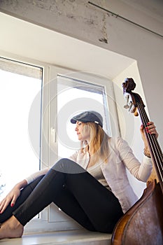 Woman barefoot on white windowsill and contrabas