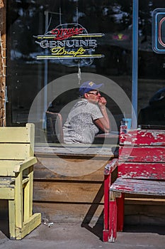 A woman with baseball cap drinks and contemplates in bar, along highway 24, central Colorado