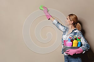 Woman with basin of detergents cleaning color wall