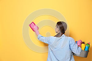 Woman with basin of detergents cleaning wall