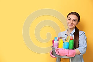 Woman with basin of detergents on color background