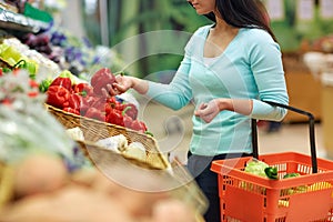 Woman with basket buying peppers at grocery store