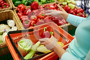 Woman with basket buying peppers at grocery store