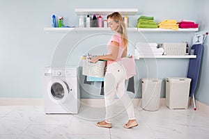 Woman With Basket Of Clothes In Utility Room