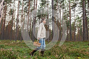 woman with basket picking mushrooms in forest