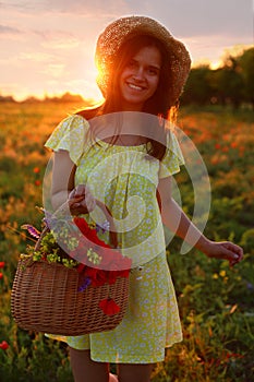 Woman with basket of poppies and wildflowers in beautiful field