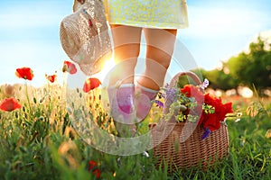 Woman with basket of poppies and wildflowers in sunlit field