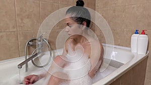 Woman in bath check water and turn off tap