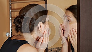 Woman in the bath crushes pimples in front of the mirror