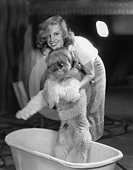 Woman bathing dog in tub