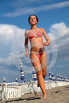 Woman in bathing suit runs on sand on beach