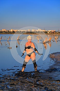 A woman in a bathing suit smeared with healing mud of the estuary