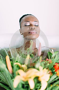 Woman bathing in a tub full of foam. Beautiful african american bride in decorated bath. Beautiful african american