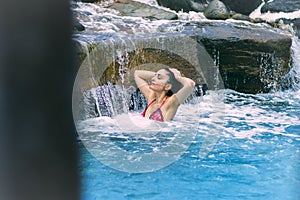 Woman bathing under a waterfall in a private pool