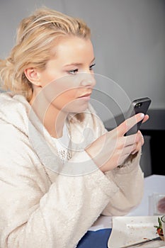 Woman in a bathrobe ckecking her mobile