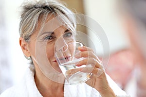 Woman in bathrobe drinking water