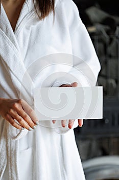 Woman in bathrobe holding an empty spa gift card for visits.