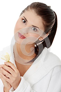 Woman in bathrobe holding orchid flower