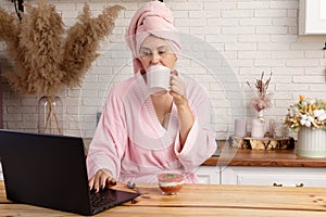 woman in bathrobe after a shower eats delicious dessert for breakfast in the home office