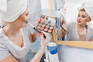 Woman in bathroom applying contour bronzer on brush