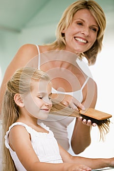 Woman in bathroom brushing young girl's hair