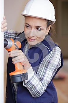 woman in bathroom with drilling machine