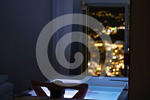 Woman in the bathroom at the hotel enjoying the view of the night city