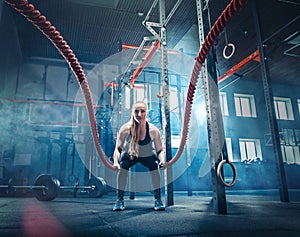 Woman with battle rope battle ropes exercise in the fitness gym.