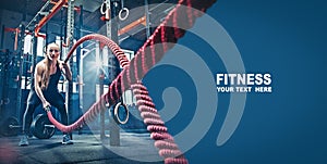 Woman with battle rope battle ropes exercise in the fitness gym.