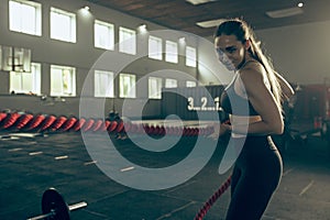 Woman with battle ropes exercise in the fitness gym.