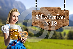 Woman in a bavarian dirndl with beer and pretzel and the text `Oktoberfest 2018`