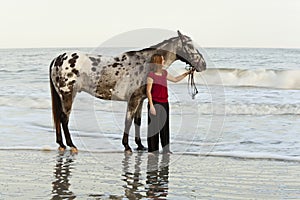 Woman on beach with appaloosa