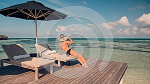 Woman on beach enjoying sunlight on sun loungers