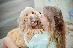 A woman on the beach with her Chocker Spaniel in front of a graffiti wall.