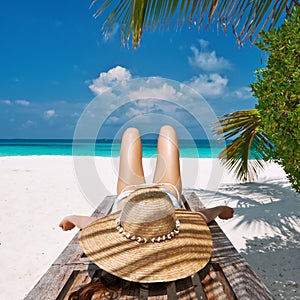 Woman at beach lying on chaise lounge